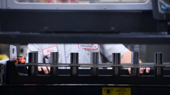 An operator loading a drawer with cylindrical parts.